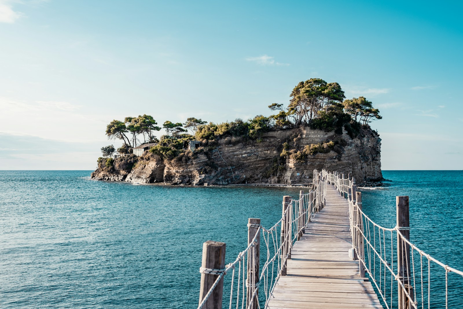brown wooden bridge over blue sea under blue sky during daytime